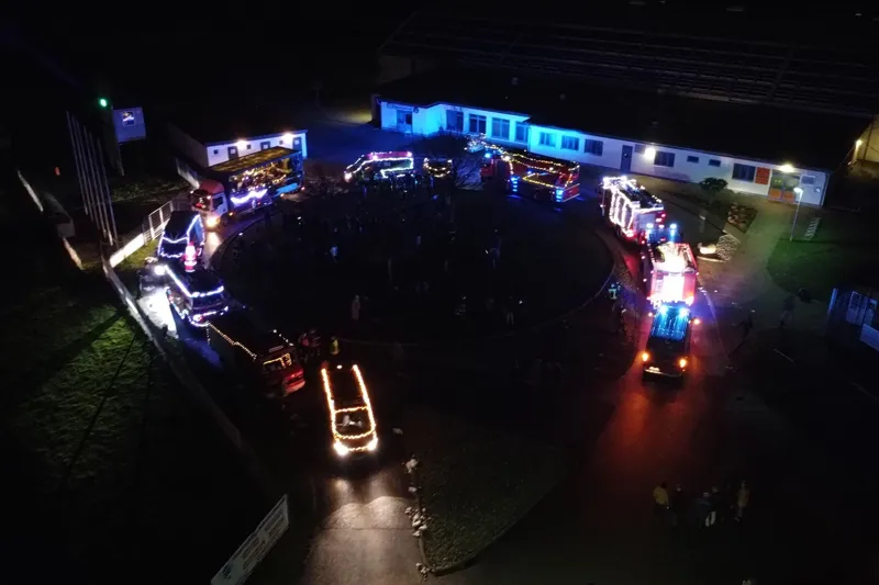Luftaufnahme: beleuchtete Wagen im Kreis bei einem Adventsfest am Abend