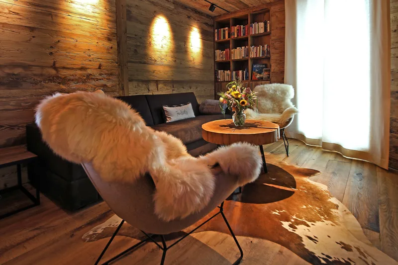 Hütten-Lounge im Chalet O mit Holz, Fellen und warmem Licht