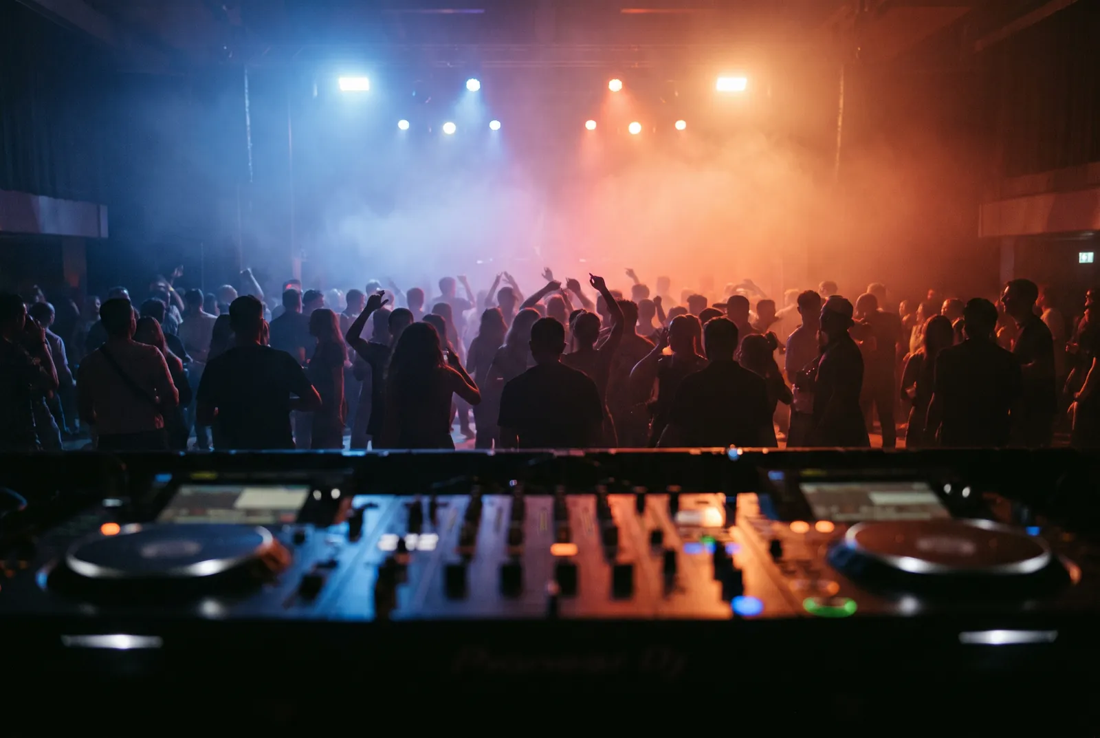 DJ am Pult vor tanzenden Gästen