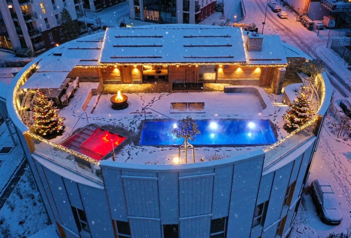 Chalet O am Winterabend aus der Luft: roter Whirlpool, blauer Pool, weihnachtlich beleuchtet