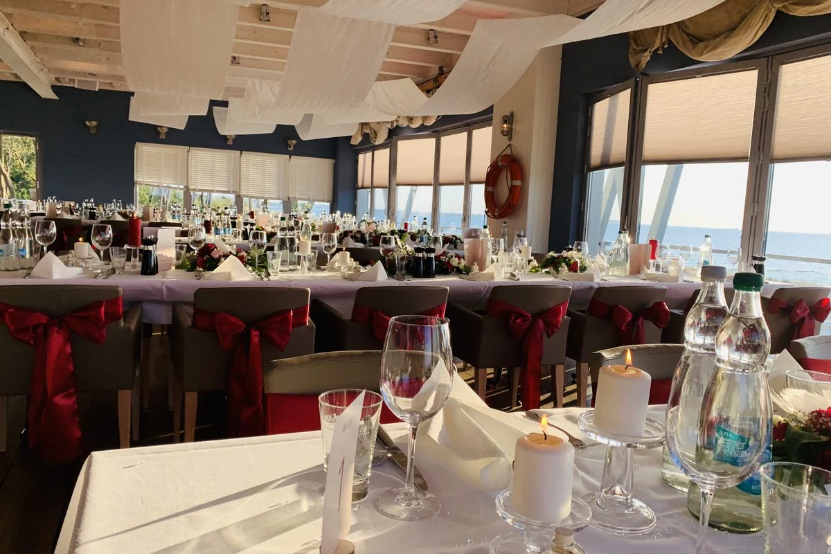 Gedeckter Hochzeitstisch mit Kerzen, Weingläsern und roten Stuhlschleifen