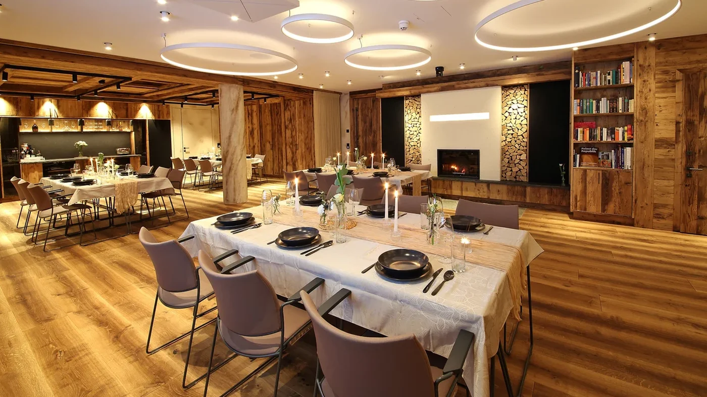 Festlich gedeckte Tafel im Chalet O am Rostocker Stadthafen mit Kaminfeuer und Almh&uuml;tten-Holzwand