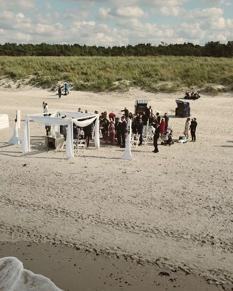 Hochzeitsgesellschaft im Zelt am Ostseestrand aus der Luft, Stuhlreihen im Sand