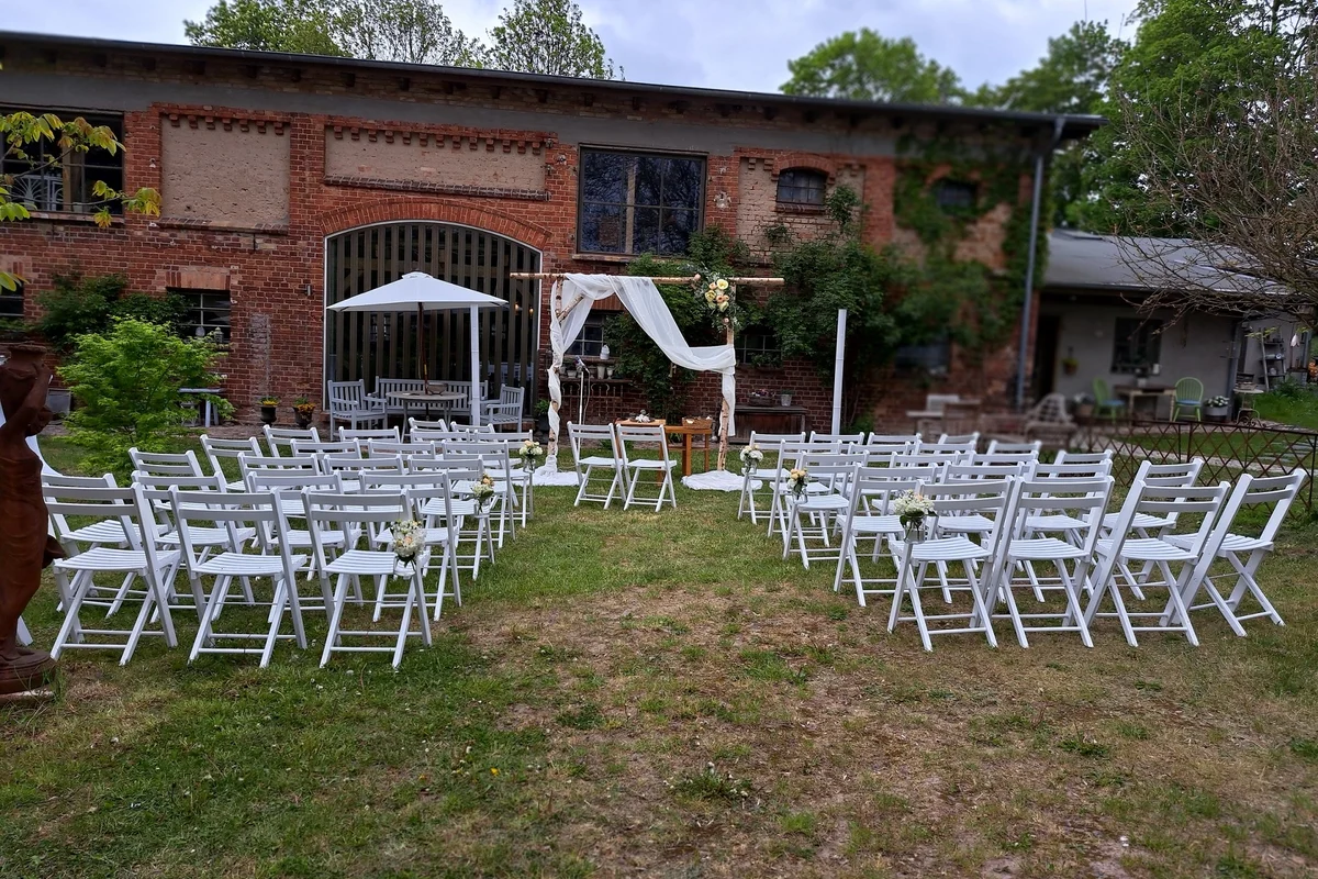 Aussenansicht des KlangAtrium Schmadebeck, Backsteingebaeude mit Trauungsbestuhlung auf der Wiese davor